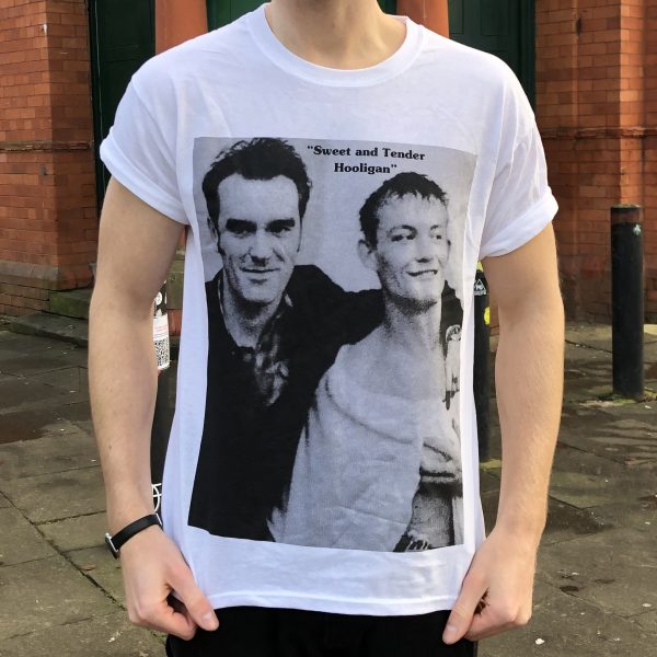 A white T-shirt featuring a rectangular black-and-white picture of Morrissey and the boxer Cornelius Carr. Morrissey (left) has his arm around the boxer (right).