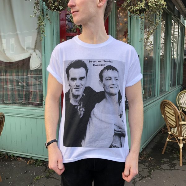 A male model wearing the 'Sweet and Tender Hooligan' T-shirt with a cafe in the background