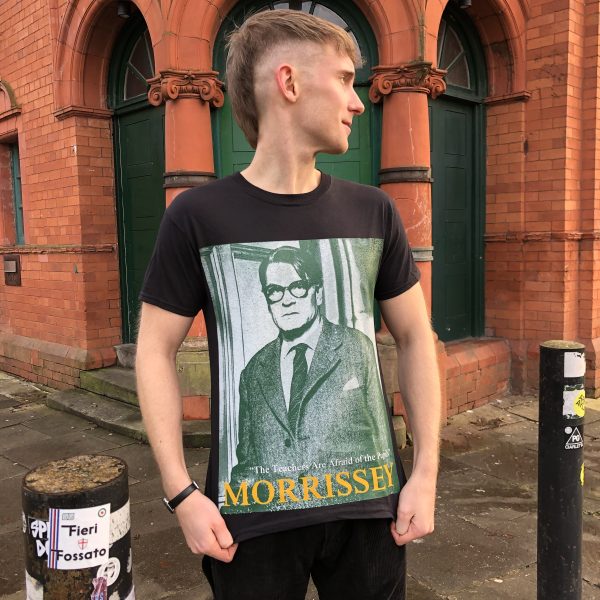 A male model wearing the 'Teachers' T-shirt with the Salford Lads Club behind him
